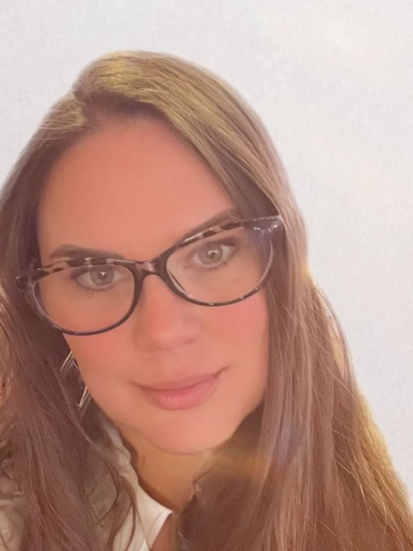 Close-up portrait of a woman with glasses and long brown hair.
