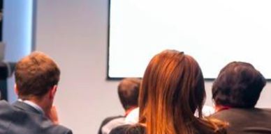 Audience attentively watching a presentation in a conference room.