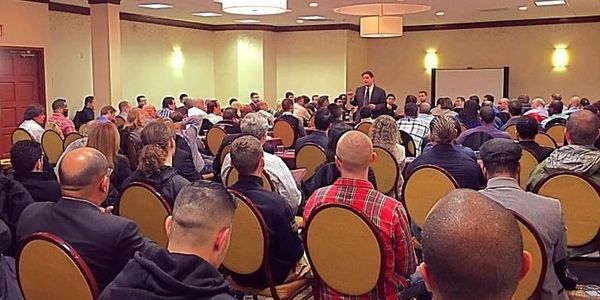A speaker addressing a large audience in a conference room.