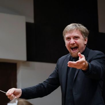 Enthusiastic male conductor directing music.