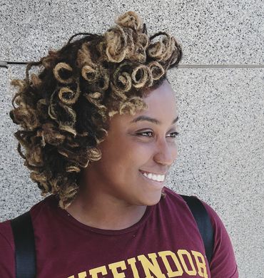 Smiling woman with curly hair and a Gryffindor shirt.