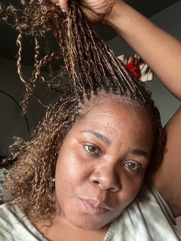 Woman holding up her braided hair, showing off curls and highlights.