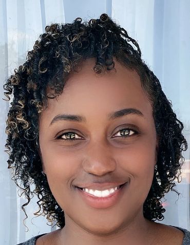 A smiling woman with curly hair and bright eyes.
