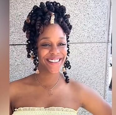 Smiling woman with styled curly hair and yellow strapless top.