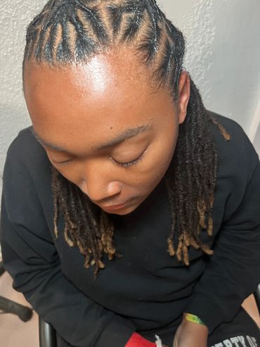 Person with intricately braided and twisted dreadlocks looking down.