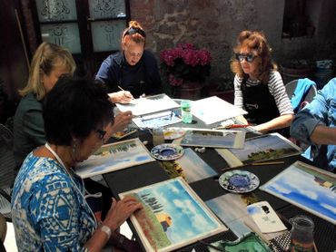 a group of people sitting at a table painting together