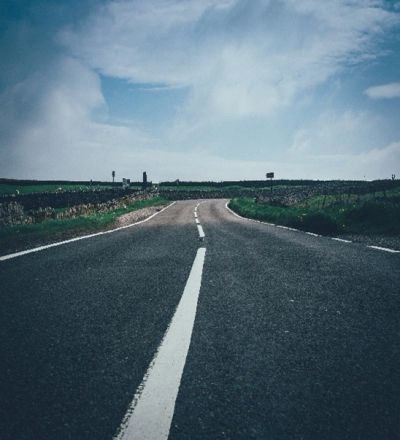 Empty country road under a partly cloudy sky.