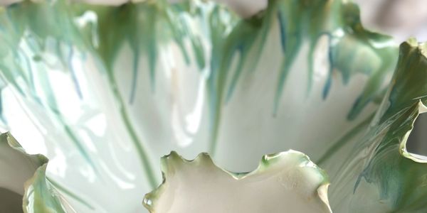 Close-up of a ceramic bowl with green and blue glaze drips.