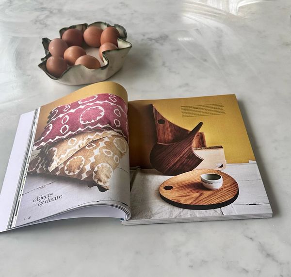 Open magazine on a marble table with eggs in a decorative bowl.
