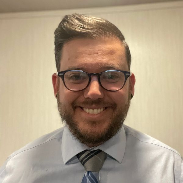 Man in glasses smiling in a shirt and tie.