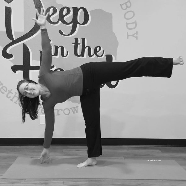 A woman practices yoga balancing on one leg with the other leg extended.