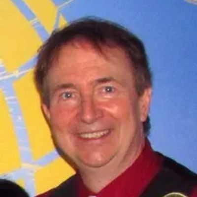 Smiling man in a red shirt against a colorful background.
