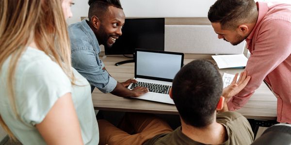 Colleagues gather around a laptop