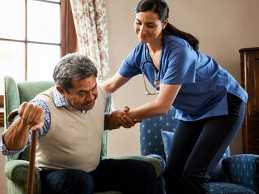 Therapist helping senior man stand.