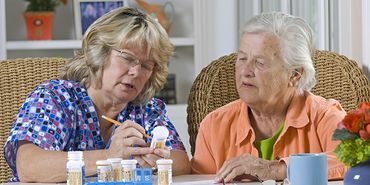 Caregiver assisting two elderly women.