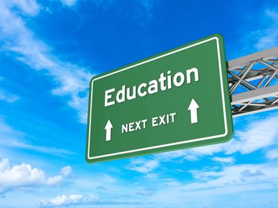 Green highway sign reading 'Education Next Exit' against a blue sky.
