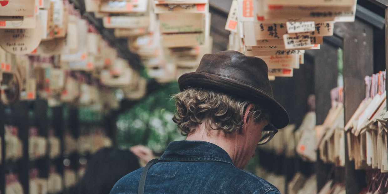 Person wearing hat and glasses in a space with hanging notes.
