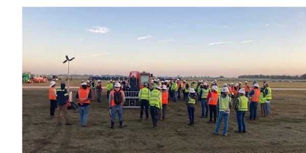 Safety briefing for workers at a construction site during dawn.