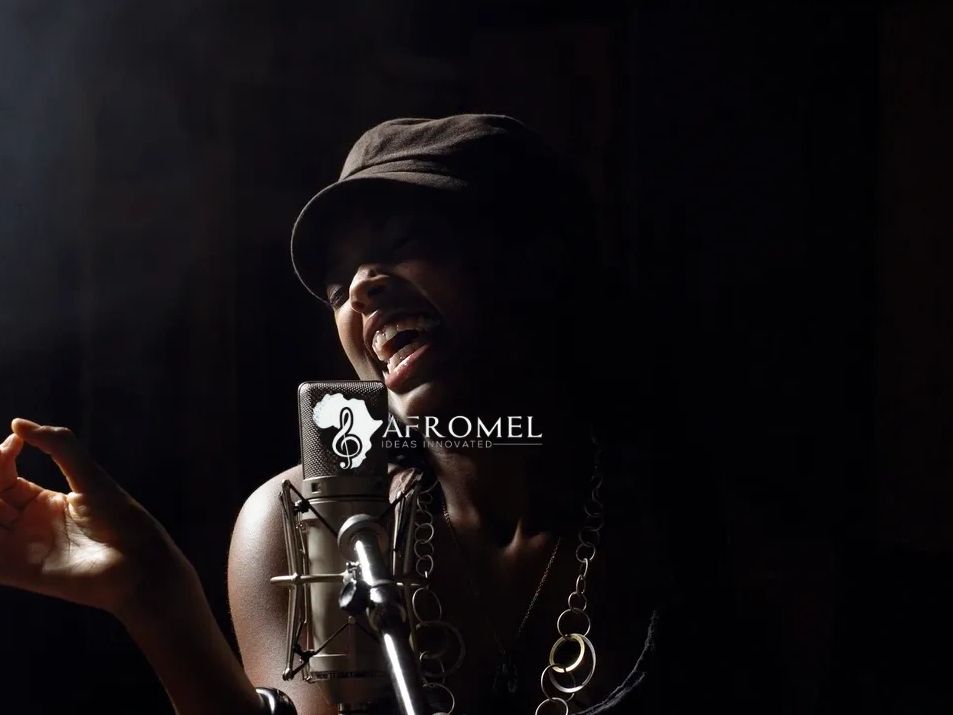 A woman passionately singing into a microphone in a dark studio.
