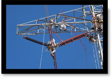 Workers repairing high-voltage power lines on a clear day.