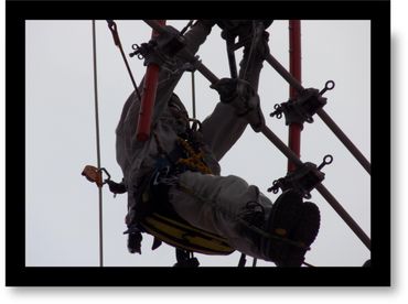 Worker suspended by harness on cables, performing maintenance or inspection.