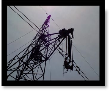 Workers climbing and repairing a tall electricity transmission tower against a cloudy sky.