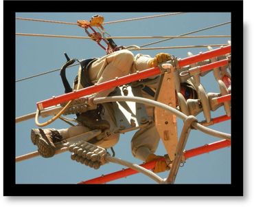 Worker performing maintenance on high-voltage power lines wearing safety gear.