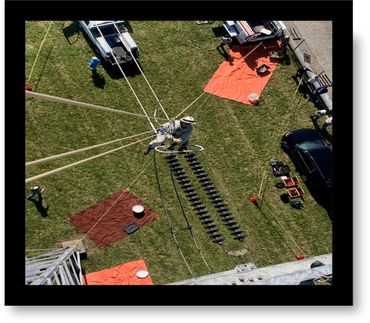 Worker suspended on wires performing maintenance on electrical equipment.