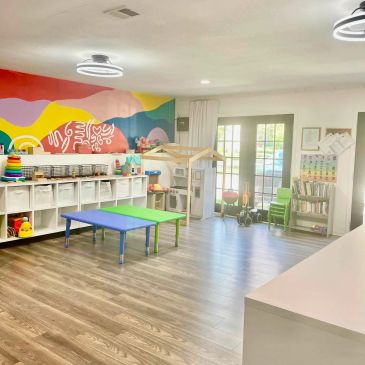 Bright, colorful children's playroom with toys and tables.