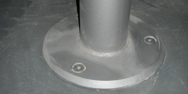 A circular mezzanine floor column with circular chamfered baseplate and countersunk fixings. 