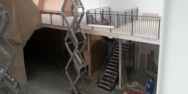 A mezzanine floor with child safe vertical bar balustrade behind an extended scissor lift.