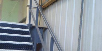 Welded and painted steel double tubular handrail on a steel staircase in a West London unit. 
