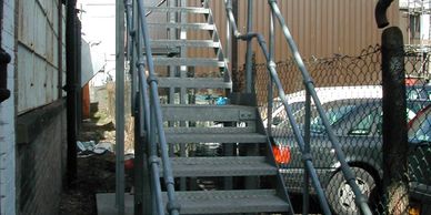 A galvanised steel external fire escape staircase with ball and tube handrail standards in London.