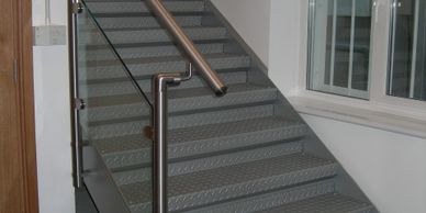 A steel staircase with stainless steel handrail and toughened glass infills in South London.