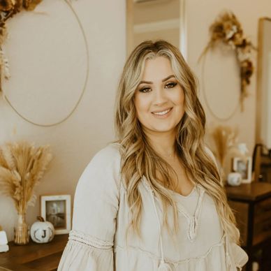 Smiling woman with long blonde hair in a cozy, neutral-toned room.