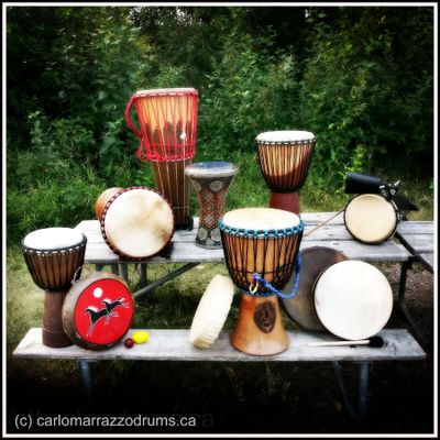 A variety of traditional drums displayed on outdoor benches.