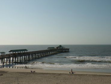 A peaceful pier extending into the ocean under a clear sky.