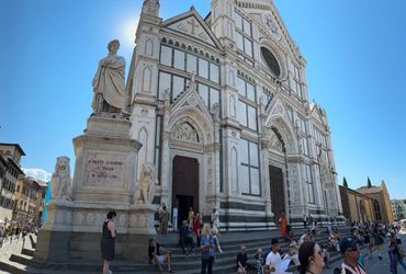 Statue of Dante Alighieri and historic church facade with visitors around.