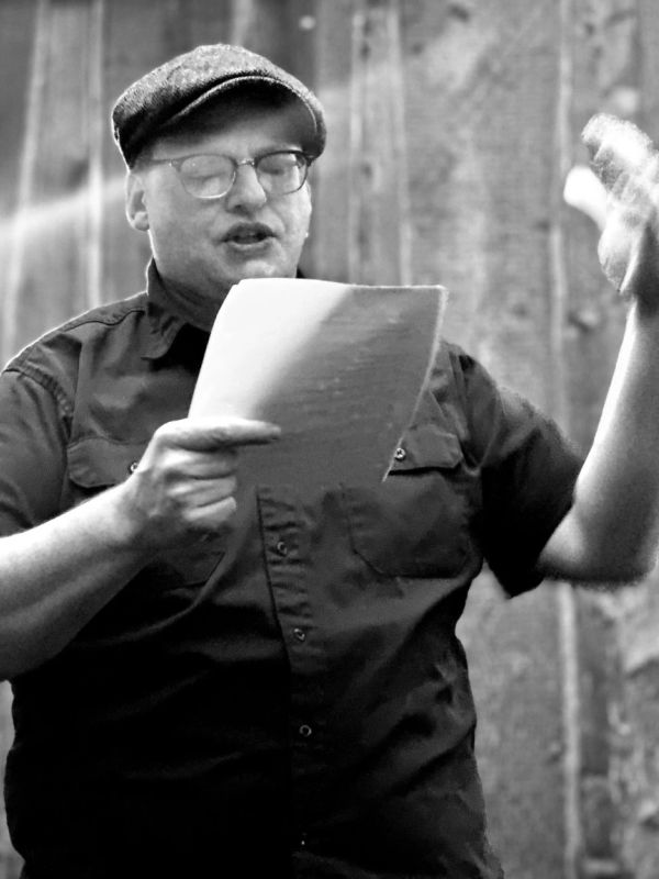 Man reading and gesturing with a paper in hand.