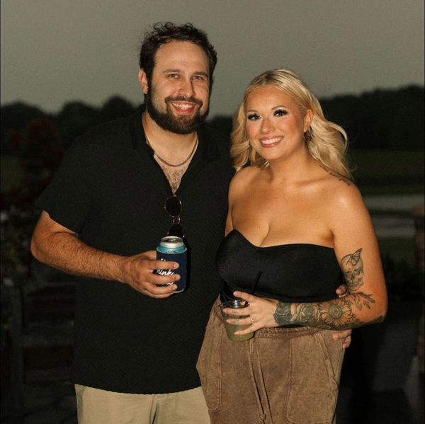 Smiling couple posing at an outdoor event with drinks.