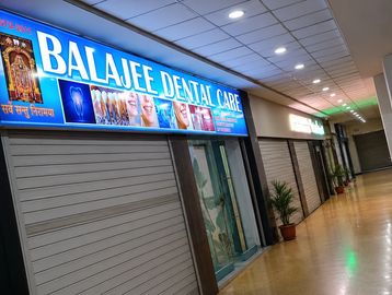 Closed dental clinics inside a corridor with bright signage for Balajee Dental Care.