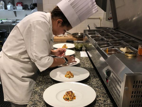 Chef plating gourmet dishes in a professional kitchen.