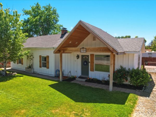 White house with wooden accents and green lawn.