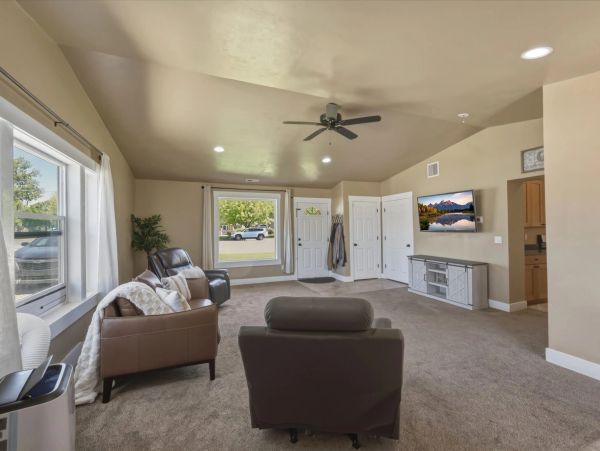 Spacious beige living room with leather chairs and wall-mounted TV.