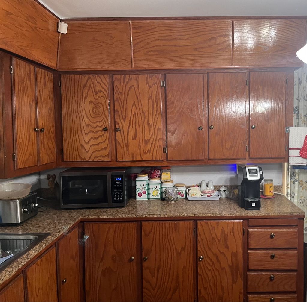 Before kitchen cabinet painting in Houma LA. Stained wood cabinets prior to transformation.