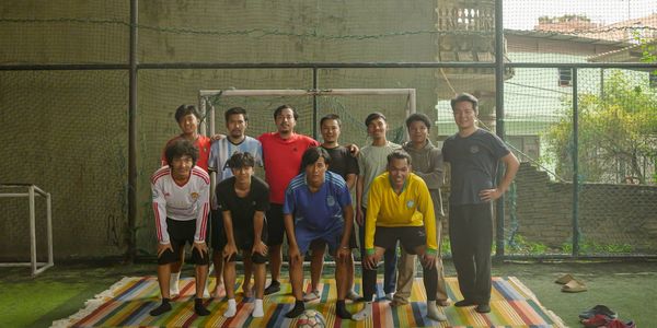 A group of men posing for a soccer team photo on an indoor field.