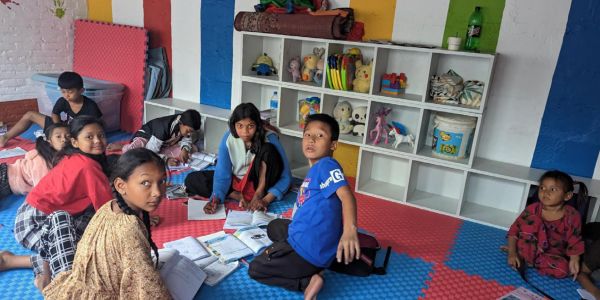 Children studying together on colorful mats in a vibrant classroom.