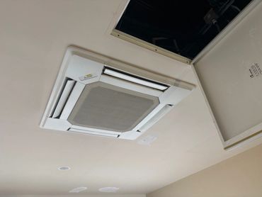 Ceiling air conditioning unit with an open access panel.