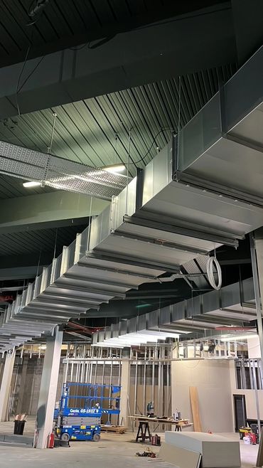 Industrial ductwork installation in a commercial building under construction.