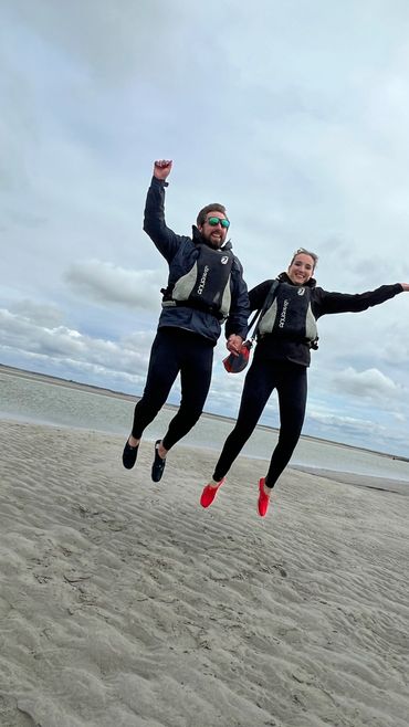 2 jeunes gens sautent en l'air sur la plage au milieu de la Baie de Somme pendant une excursion en p